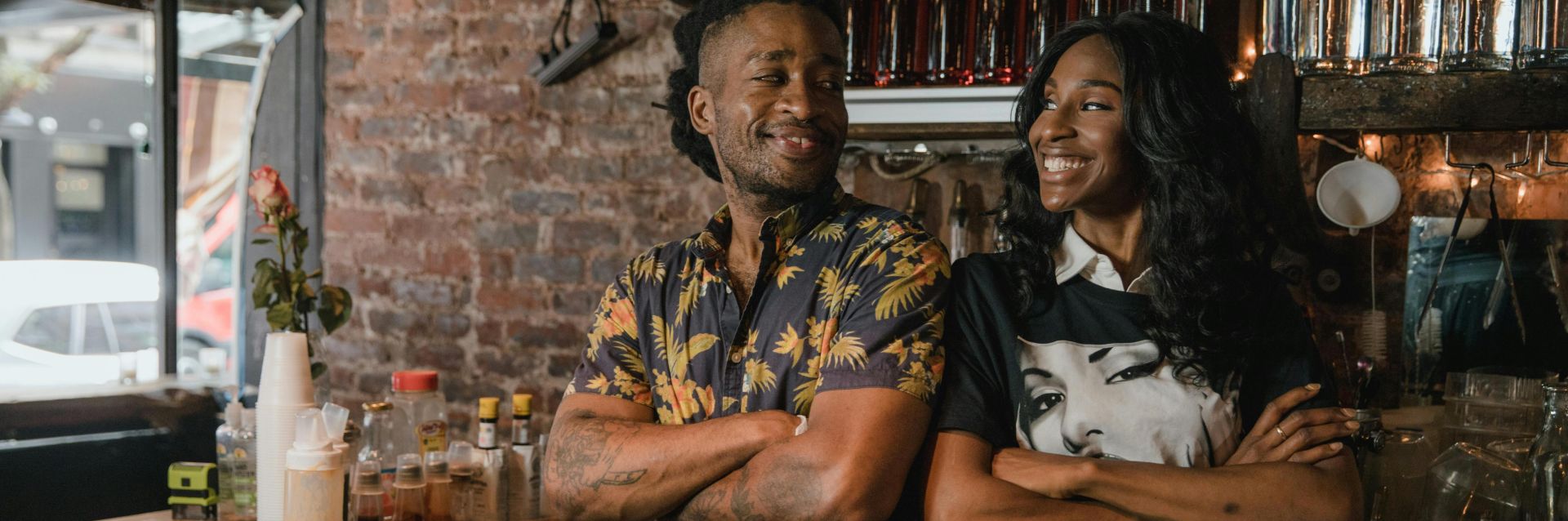 Two Black business owners smiling confidently behind a bar with oysters, embodying success and pride.