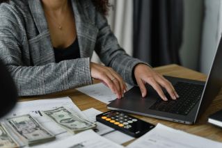 A businesswoman working on finance management with cash and calculator on desk.