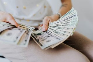 Close-up of hands holding and counting US dollar bills indoors.